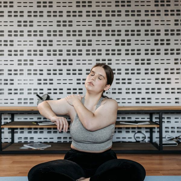 Person smiling and stretching in a calm, minimalist environment.